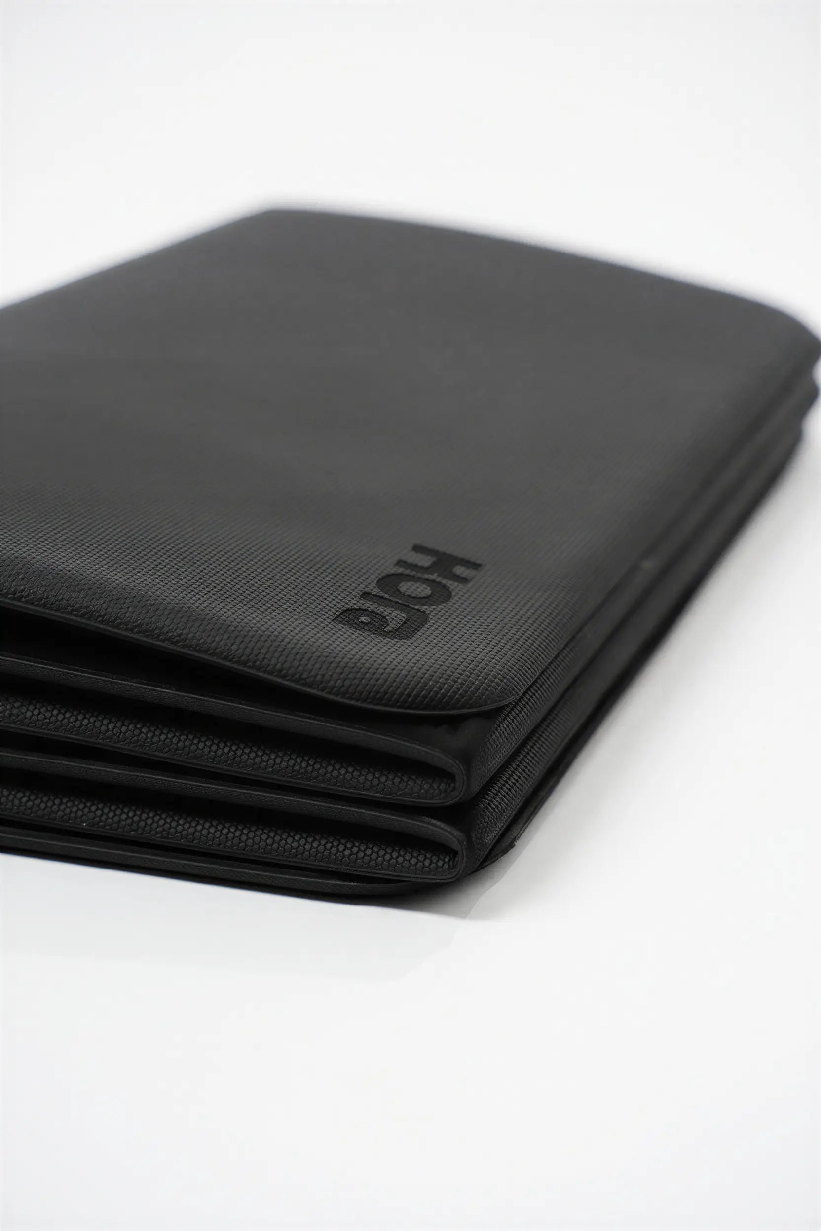 Folded black mat with 'KORA' branding on a white background