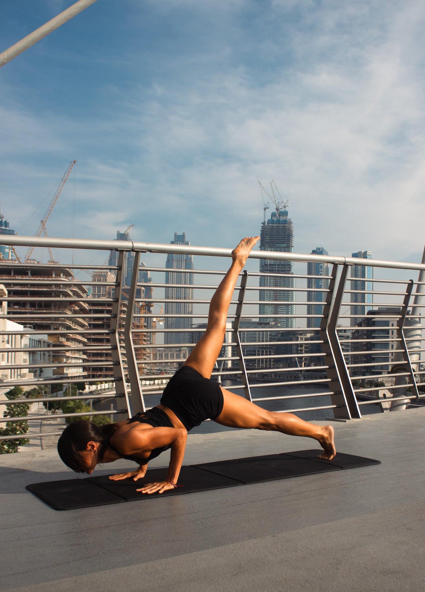 Person doing a yoga pose on a rooftop with city skyline in the background